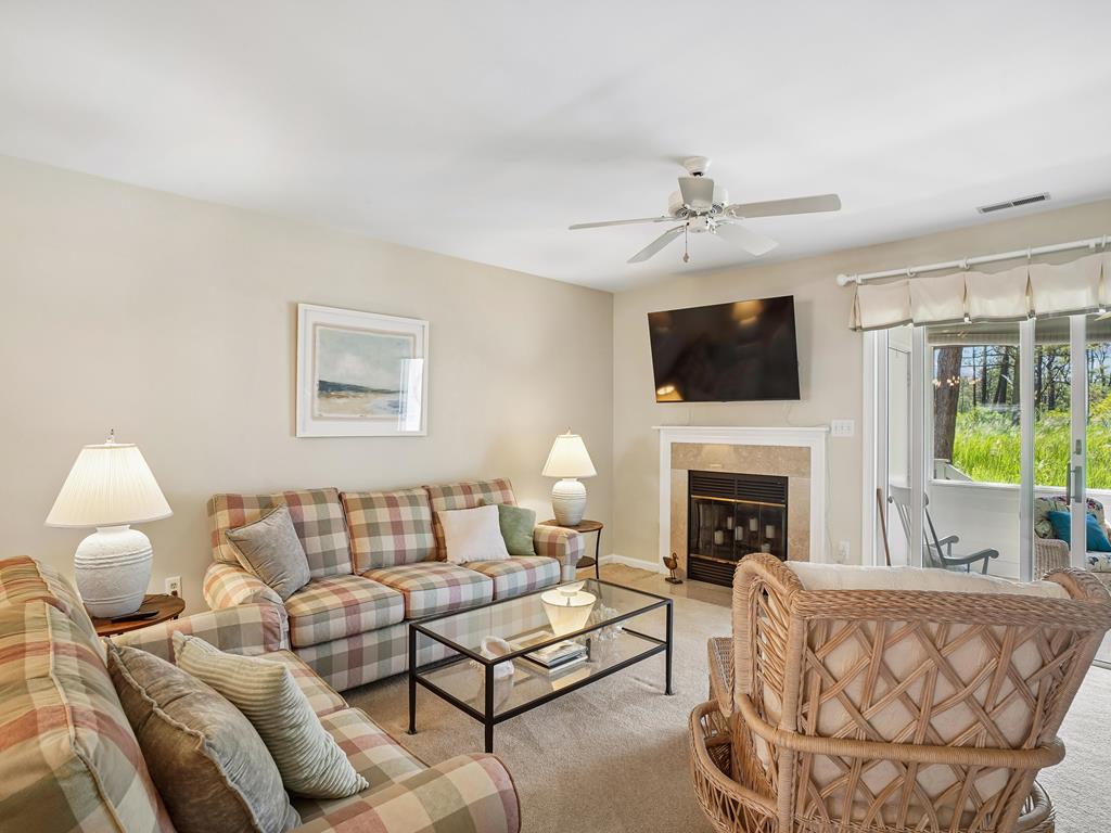 image Plaid sofas and wall-mounted Smart TV in the living room, with sliding doors leading to the screened-in porch