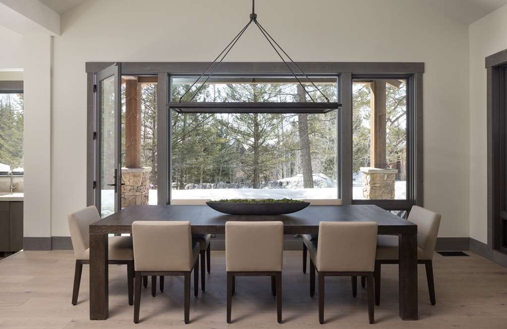 image Long enough for the whole group, this dining table sits beneath windows framing the pines.