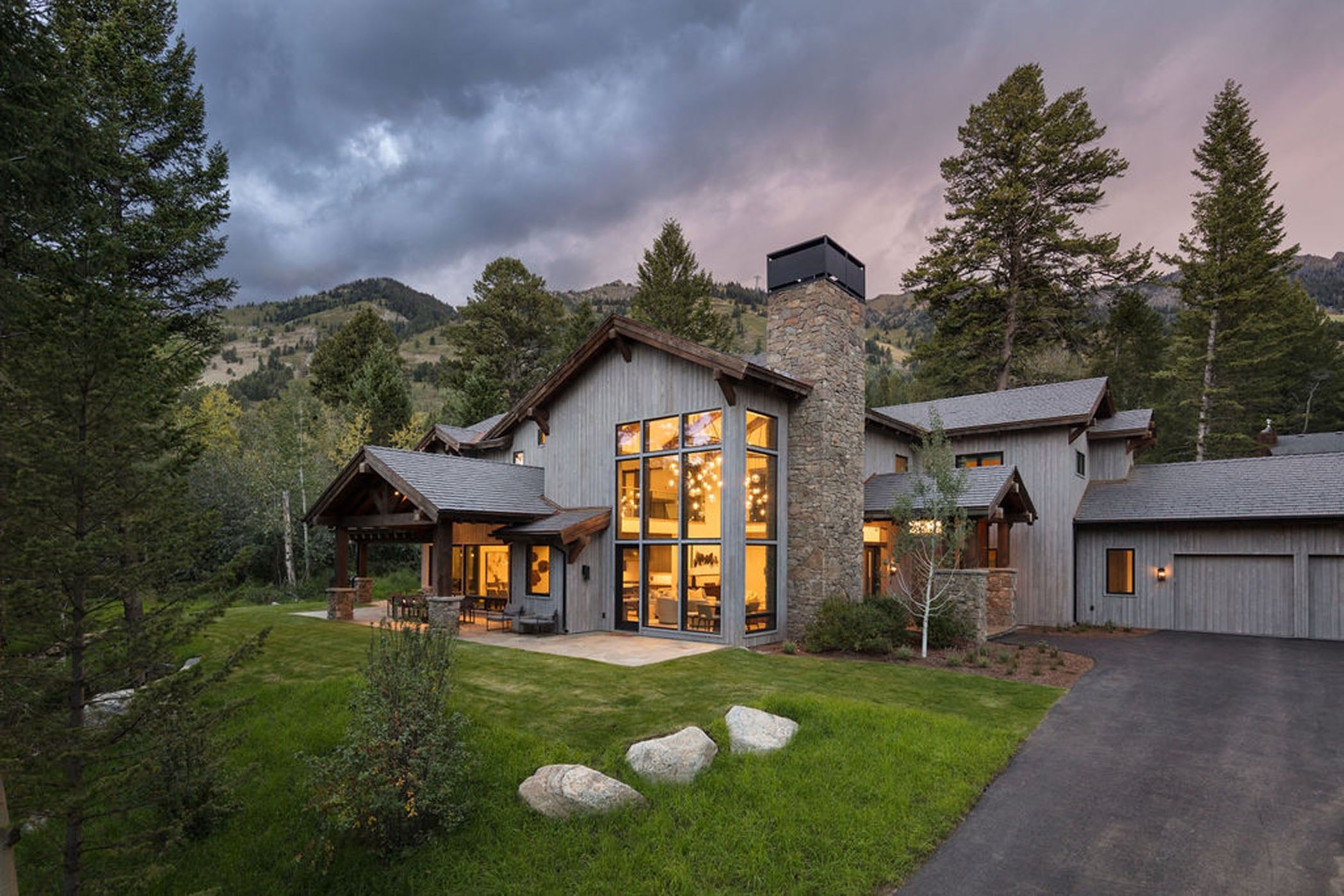 image Timber and stone details define the front of the home at dusk.