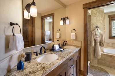 Dual sinks sit above granite countertops in this bathroom, framed by wood accents and natural light.