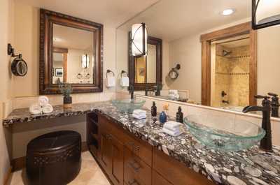 Glass bowl sinks top a double vanity with dark wood cabinetry.