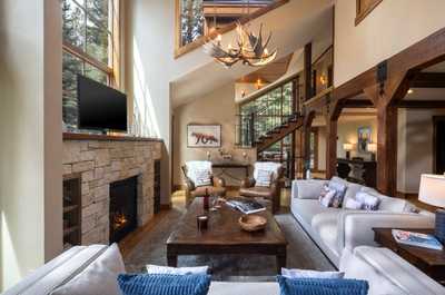 Wood beams cross the ceiling above the stone fireplace, with plenty of seating for the group.