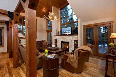 Floor-to-ceiling windows fill the living area with light, framing the stone fireplace at its center.