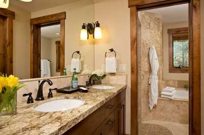 Dual sinks sit above granite countertops in this bathroom, framed by wood accents and natural light.