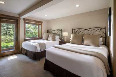 Two queen beds sit beside large windows looking out onto the trees.