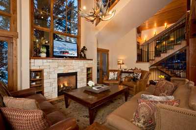 Wood beams cross the ceiling above the stone fireplace, with plenty of seating for the group.