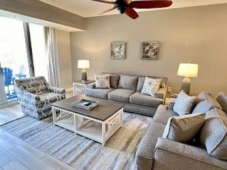 image Light gray living area with a spacious sofa set, coffee table, and sliding glass doors to the outdoors