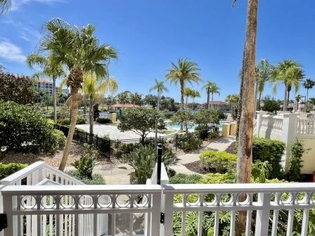 image Balcony view of the pool, manicured gardens, and palm trees on a clear Florida day