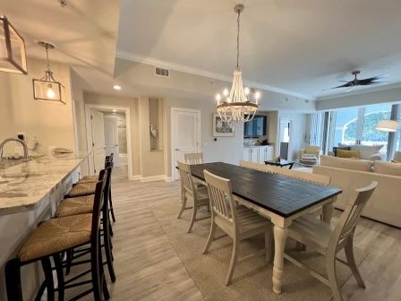 image Dining area with a long dark wood table, white chairs, and a chandelier overhead