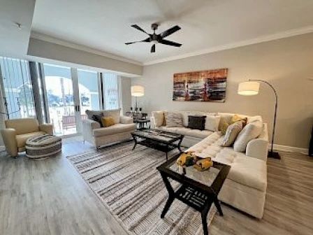 image Light-filled living area with a beige sectional sofa, coffee table, and large windows