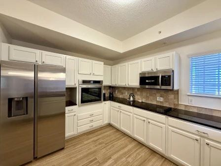 image Kitchen with white cabinetry, black countertops, and stainless steel fridge and microwave