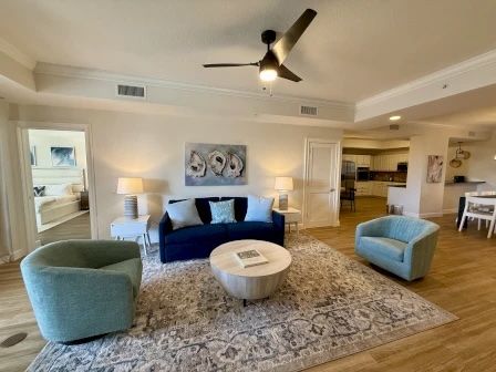 image Living room with a blue sofa, light blue armchairs, a round coffee table, and two lamps on an area rug