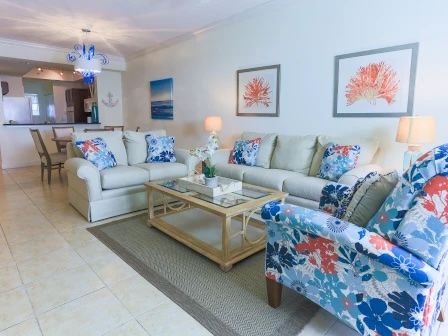 image Living room with two floral-patterned sofas, a wooden coffee table, and coral artwork on the walls
