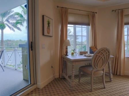 image Office nook with a light desk, chair, and large window overlooking palm trees outside