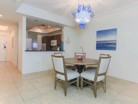 image Dining area with a round wooden table, four upholstered chairs, and a chandelier above