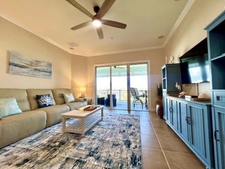 image Living area with a tan sofa, blue rug, and sliding glass doors opening to the ocean balcony