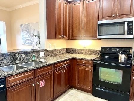 image Kitchen with dark wood cabinets, granite countertops, double sinks, and a black stove