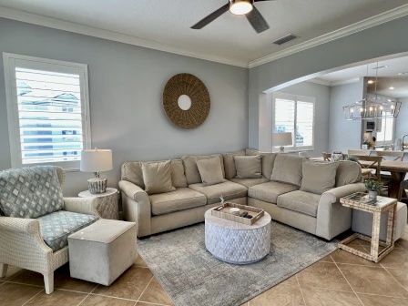 image Living room with a neutral sectional sofa, round coffee table, and a mirror on the light grey wall