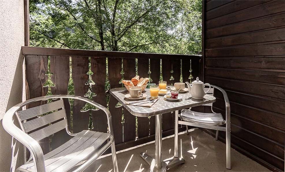 image The balcony table looks toward the trees leading up to the Ax-Bonascre gondola, in any season.