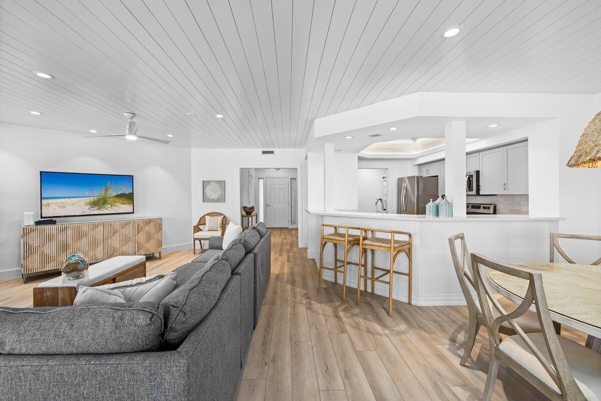 image Wood dining table and a couch share the living area, a ceiling fan spinning above.