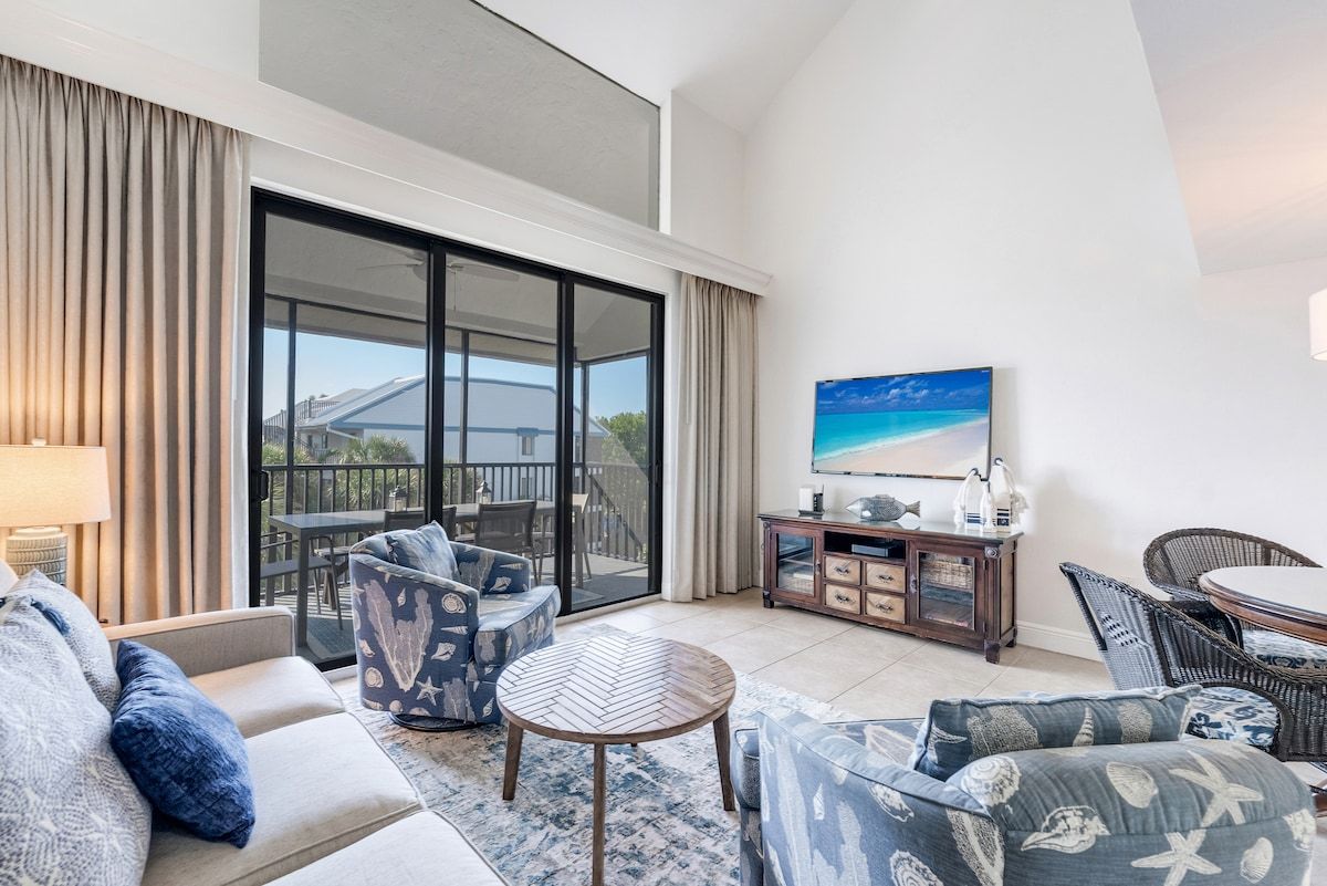 image Coastal-inspired living area with comfortable seating, a TV, and access to a screened balcony.