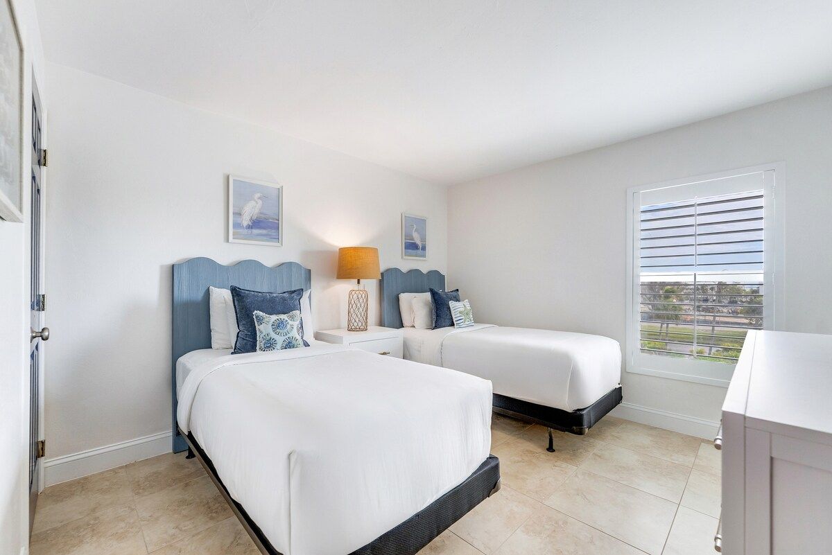 image Spacious bedroom with two beds, bedside lighting, and plenty of natural light.