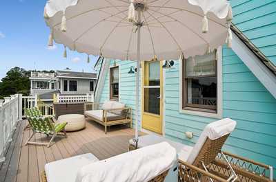 Outdoor deck with lounge chairs and a canvas umbrella in a lush setting.