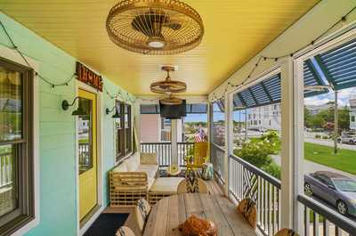 Covered porch with a dining table and comfortable wicker seating for gatherings.