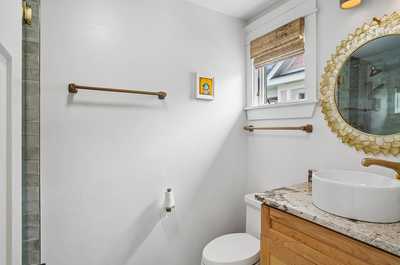 Clean bathroom with a vessel sink, round mirror, and warm natural light.