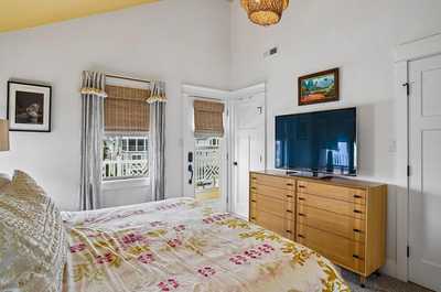 Bedroom with a wall-mounted TV, wooden dresser, and natural wood textures.
