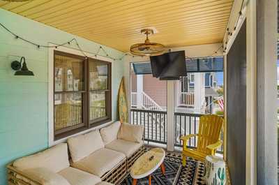 Breezy front porch with soft seating and a glimpse of the neighborhood beyond.