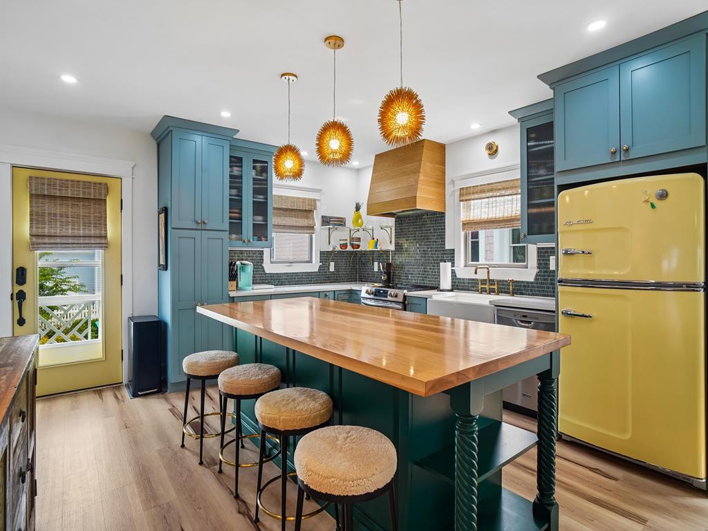 image Vibrant kitchen with bold teal cabinets, a yellow fridge, and wooden counters.
