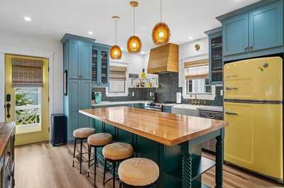 Vibrant kitchen with bold teal cabinets, a yellow fridge, and wooden counters.