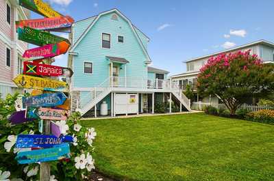 Whimsical directional signpost nestled among tropical blooms and lush greenery.