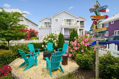 Whimsical direction signs clustered in a flower-filled outdoor gathering space.