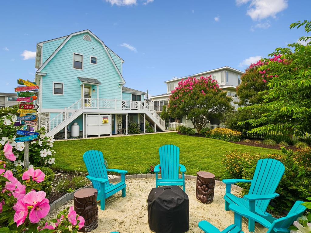 image Lush garden seating area backed by colorful blooms and a green hedge.