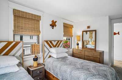 Bright bedroom with warm wood tones, wall art, and a dresser with storage.