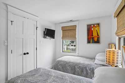 Two beds with playful ocean-themed decor and natural light from dual windows.