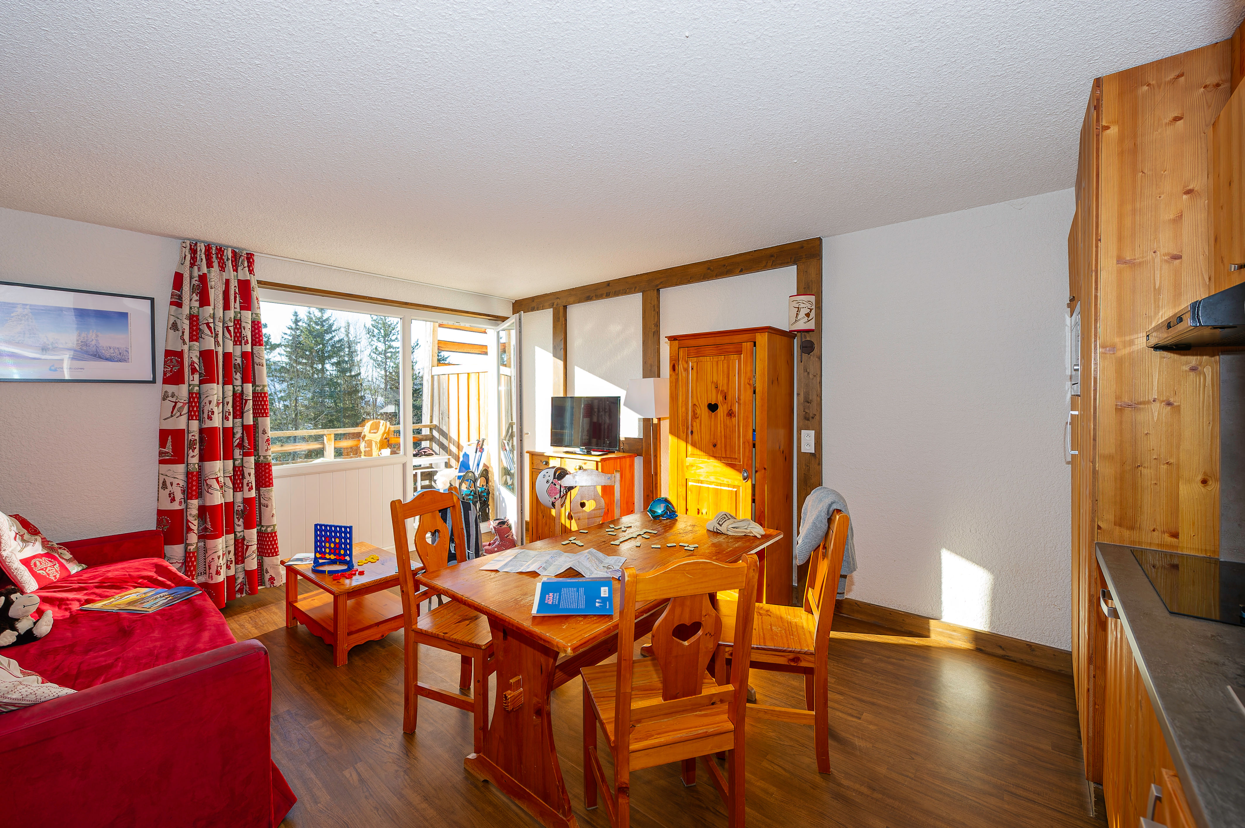 image Living area with a red sofa, wooden dining table and large windows