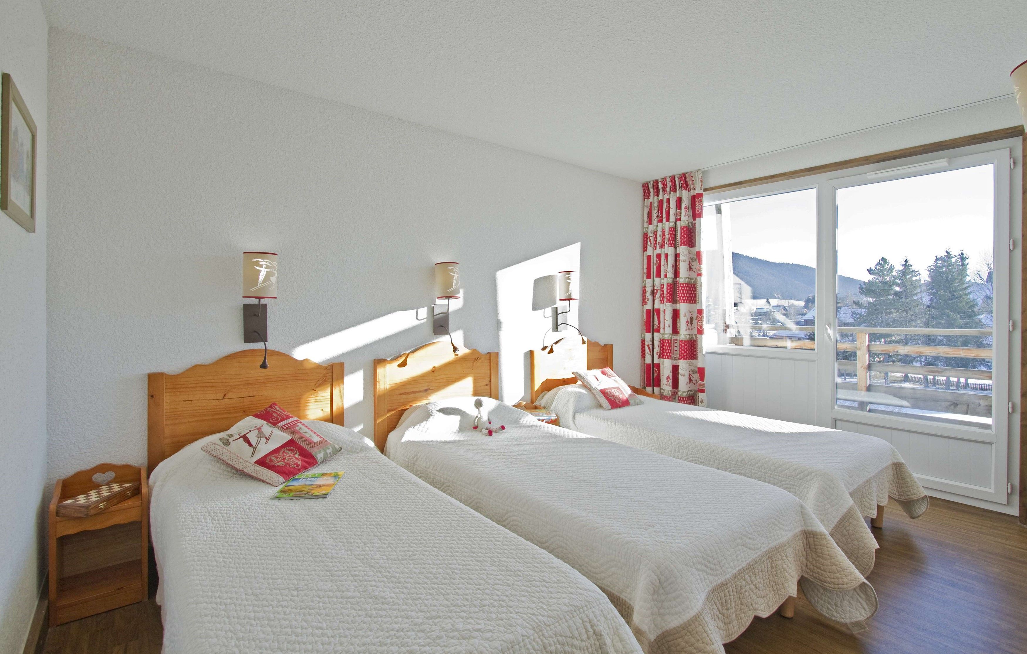 image Bedroom with two single beds, bedside tables and large windows