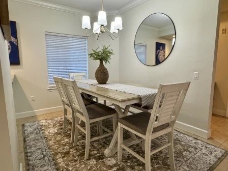 image Dining table beneath a statement light fixture, with fresh greenery and views to the balcony