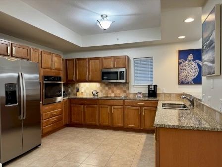 image Kitchen with rich wood cabinetry, polished granite counters, and full-sized stainless appliances