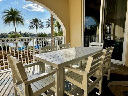 image Outdoor dining set on the balcony overlooking the community pool and palm trees