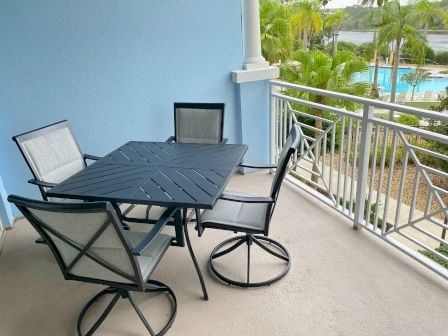 image Private balcony with seating and open views to the pool and palm-lined waterway beyond