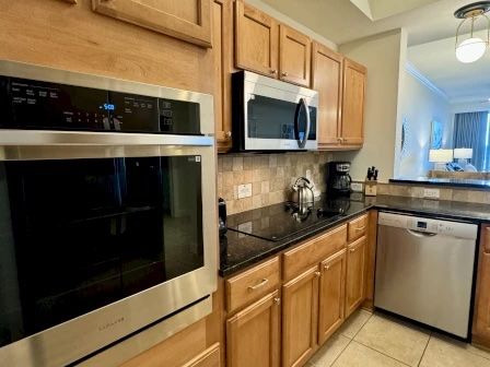 image Kitchen with stone counters, kitchen bar seating for three, and full-sized stainless appliances