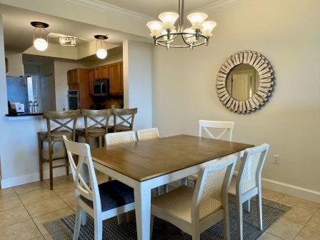 image Dining table beneath statement pendant lights — open to the kitchen and living area