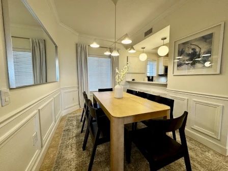 image Dining table for six beneath warm pendant lighting — open to the kitchen and living area