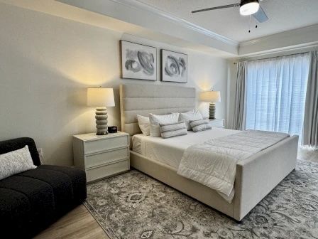image King master bedroom with soft neutral tones, a seating nook, and natural light from the window