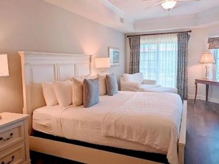 image King master bedroom with soft white bedding and a sitting area near the window