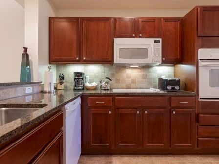 image Kitchen with rich wood cabinetry, granite counters, and full-sized appliances for group cooking
